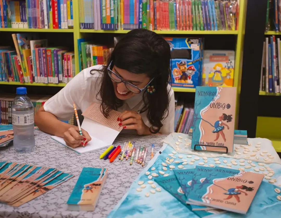 Lua Lordelo autografando exemplares físicos de Memórias de Umbigo